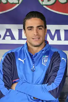 Portrait photograph of Matri smiling with crossed arms while wearing a sport jacket