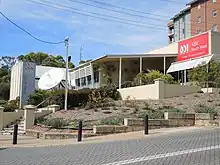 a building with the name ABC South West and a satellite dish on the side. There is a retaining wall and a small garden in front.