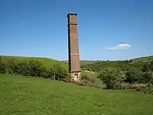 A tall brick chimney surrounded by green fields