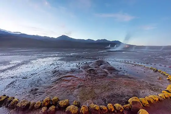 The vent is a small cone surrounded by yellow rocks in an unvegetated landscape