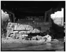 View of abutment from under bridge: Detail of both double Burr Arches beating on stone abutment (Note damage to abutment)
