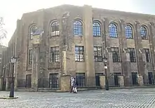 Large, old brick building, with two people for scale