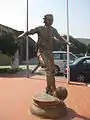 Statue of a footballer in sports facility gate.