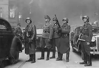 NARA copy #43, IPN copy #43The leader of the grand operationSecond from left Stroop; background either Karl Kaleske&nbsp;[pl] (Stroop's adjutant) or Erich Steidtmann; 2nd from right Heinrich Klaustermeyer; far right Josef Blösche and others at Nowolipie 64 / Smocza 1 intersection
