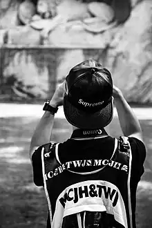 Image 36A man wearing a leather Supreme snapback hat while taking a photograph in 2016  (from 2010s in fashion)