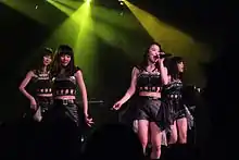 Four women in matching outfits under stage lights