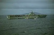 A color photo of an aircraft carrier at sea from a distance