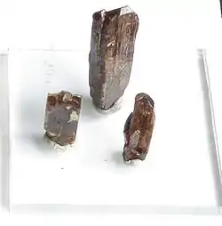 Three column shaped brown crystals on a white background